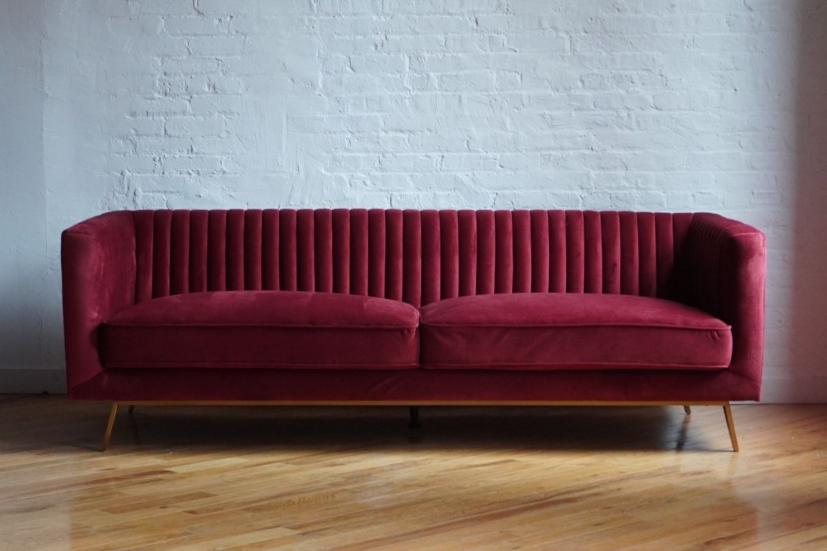 couch with vertical channel tufing in brick red velvet