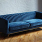 Stately navy blue velvet ribbed couch with gold legs, product image angled view