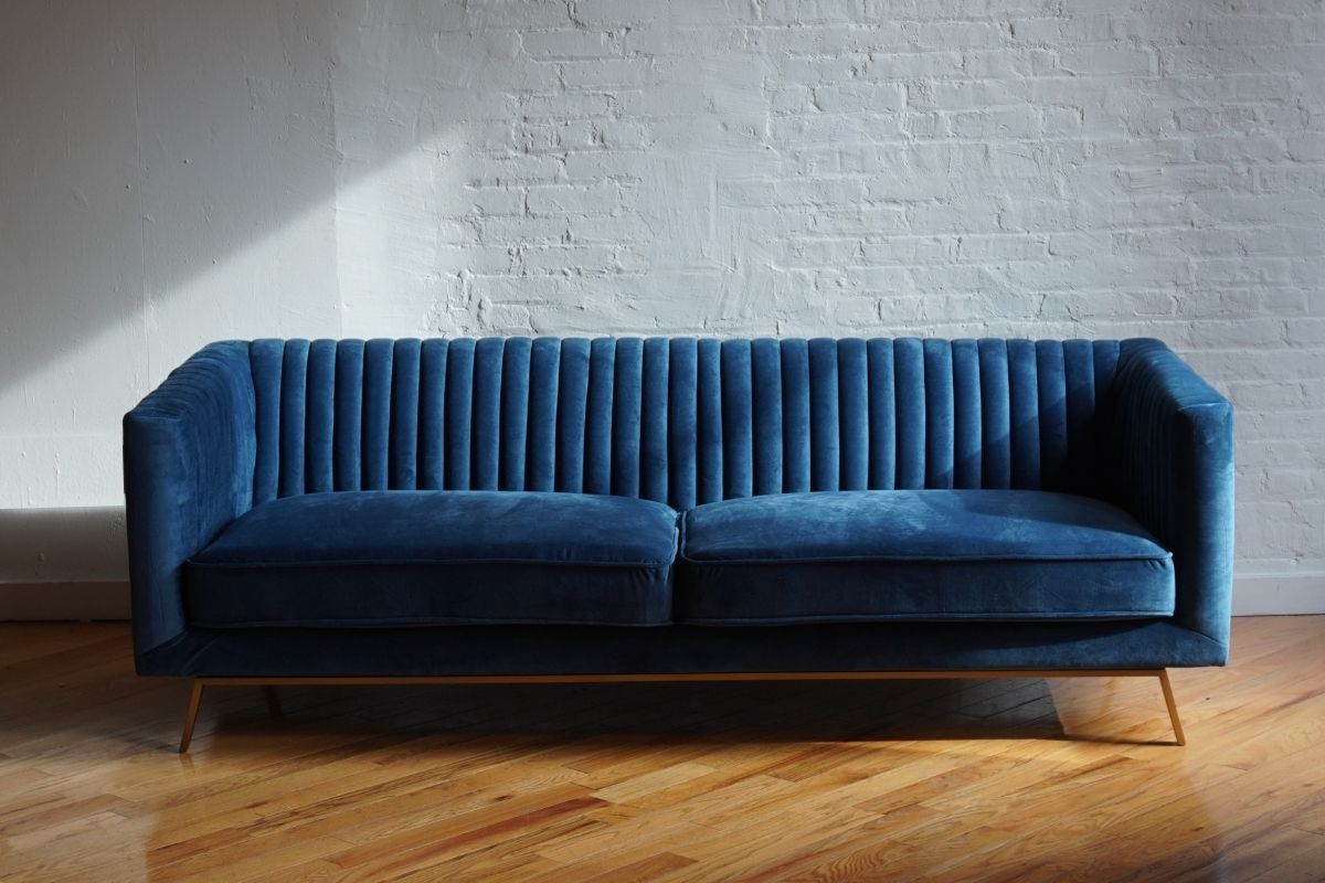 Stately navy blue velvet ribbed couch with gold legs, product image front view